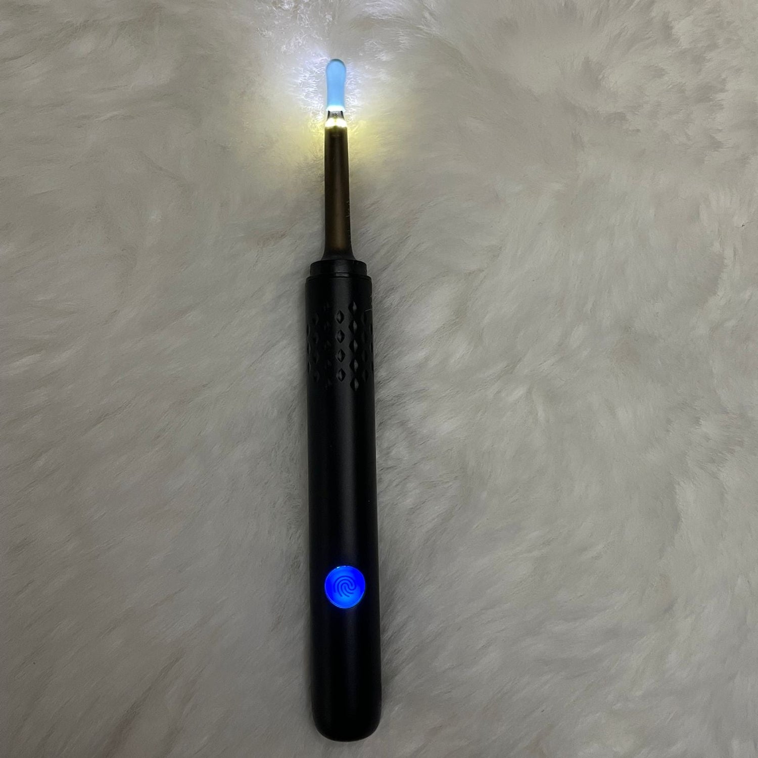 Black electronic device with headlight at the tip, on a white fur surface
